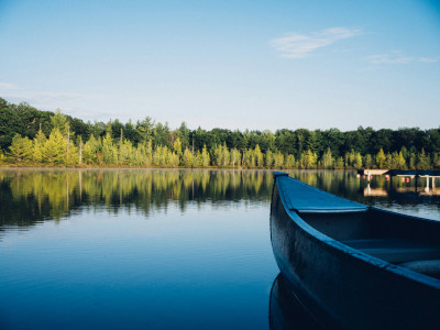 Titelbild: Bild mit See und Bäumen - ein kleines Boot ragt rechts unten ins Bild
