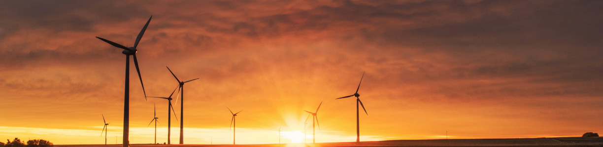 Titelbild: Bild mit Windrädern im Sonnenaufgang