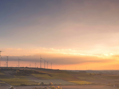 Titelbild: Ein Bild mit Windrädern mit Sonnenstrahlen auf der rechten Seite